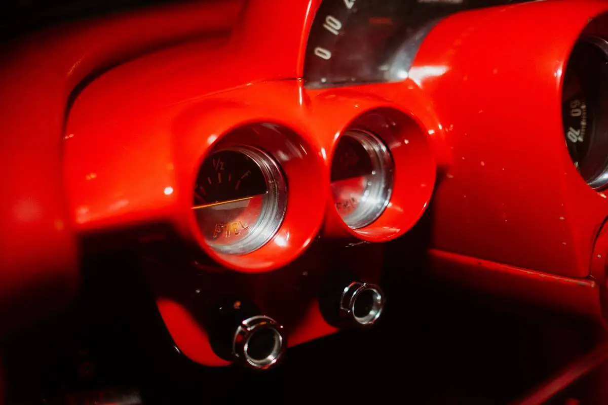 Image Description: A close-up image of a car's dashboard with a red dot symbol illuminated on the screen and a red circle symbol illuminated on another part of the dashboard.