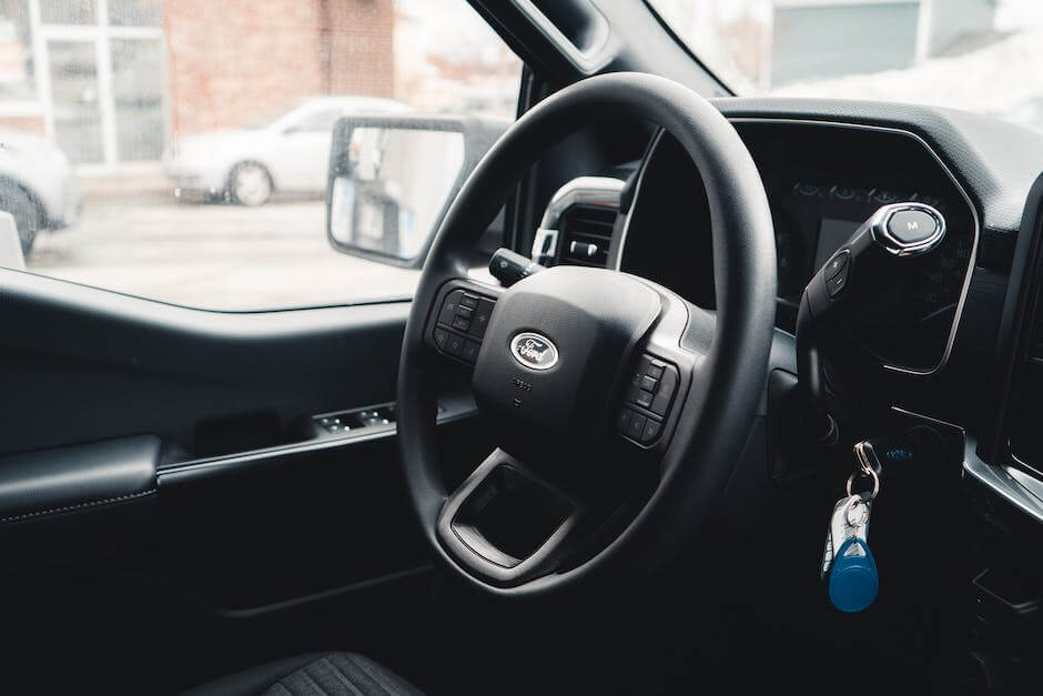 A person holding up a remote start system key fob, with a car in the background.